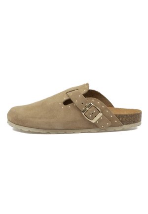 Zueco de ante marrón claro tipo slip-on con correa ajustable con hebilla, detalles con tachuelas, plantilla de corcho y suela de goma texturizada.