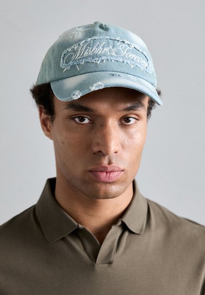 Blue denim baseball cap with distressed details and embroidered "Mishka Forever" text. Soft texture, curved visor, and adjustable strap.