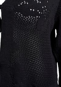 Črna pletena majica s odprtim vzorcem. Ima teksturiran zaključek in različne velikosti šivov, kar ustvarja lahko in zračnen dizajn.