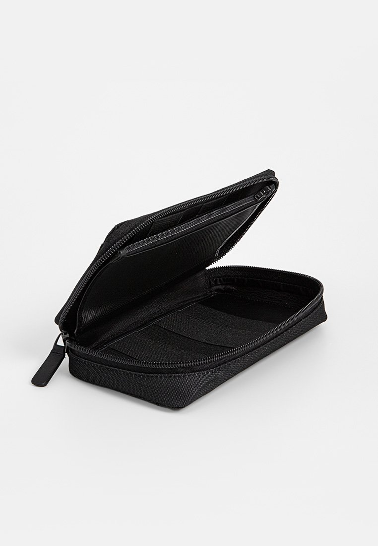 Busta nera con zip, esterno in tessuto, dotata di un compartimento aperto, fasce elastiche e una texture interna liscia.