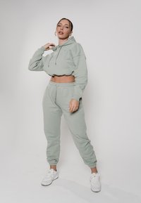 Mintgrüner, baumwollener, cropped Hoodie mit einer Fronttasche, kombiniert mit passenden Jogginghosen mit einem elastischen Bund und Bündchen.