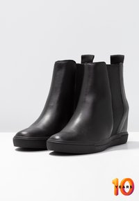 Zwarte leren enkellaarsjes met elastische zijpanelen, een afgeronde neus en een sleehakzool. Gladde textuur en minimalistisch ontwerp.