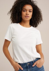 Witte korte mouwen t-shirt van zacht stof met een ronde halslijn, gecombineerd met blauwe denim jeans. Minimalistisch ontwerp, geen zichtbare patronen.