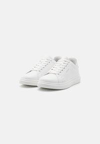Pair of white low-top sneakers with laces on a plain white background, showing side and front views.