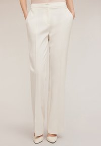 Pantalones de pierna ancha color crema, hechos de una tela suave, con bolsillos laterales y un corte recto con sutiles pliegues frontales.
