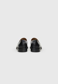 Black leather shoes with a low heel, rounded toe, and smooth finish, featuring subtle stitching details and a classic design.