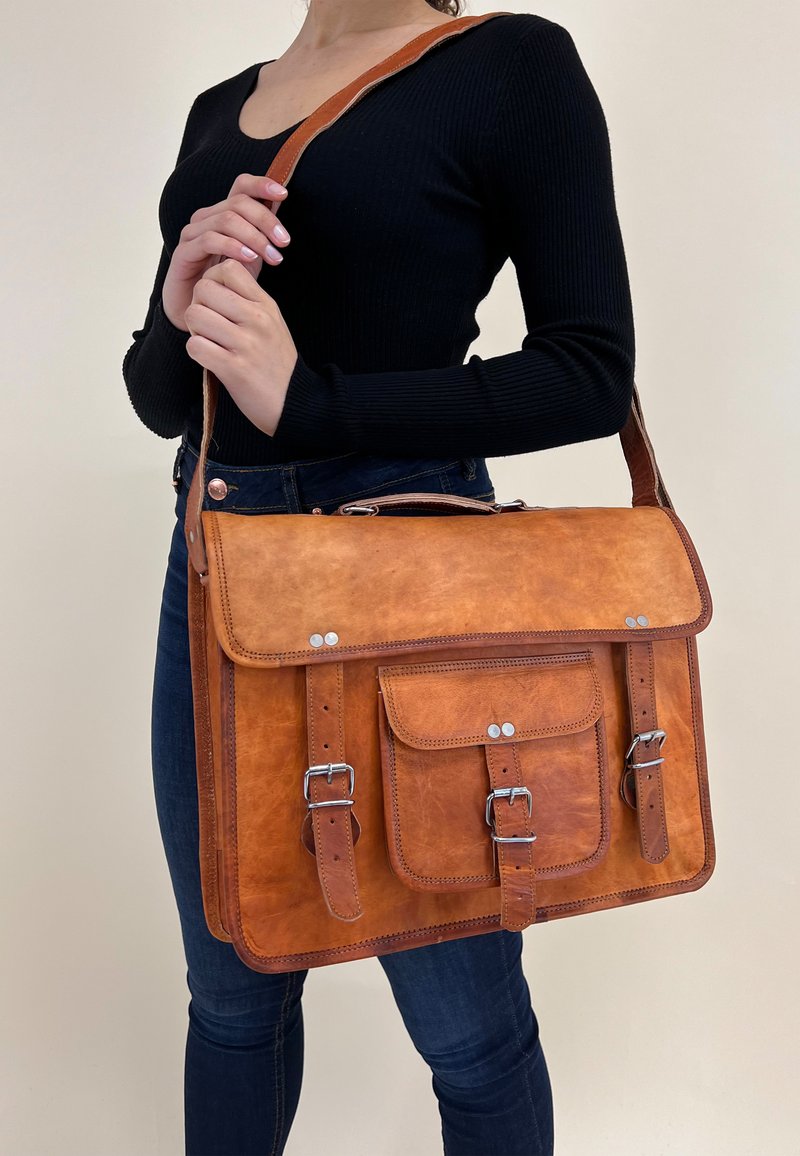 Brun læder budetasker med en frontklap, to spændebånd og en frontlomme. Tasken har en glat overflade og sølvfarvede hardware-akcenter.