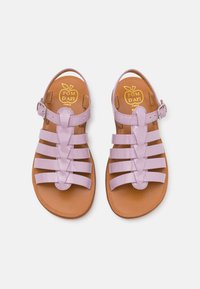Lilla patentlær sandaler med flere remmer, justerbar ankelspenne og brun teksturert såle. Logo synlig på innersålen.