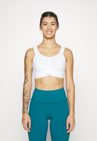 Hvit sports-BH med brede stropper og en rund hals, med et teksturert design. Kombinert med teal høy midje leggings.