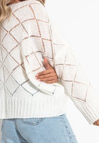 Weißer Strickpullover mit Rautenmuster, lockerer Passform und geripptem Saum. Leichtes, atmungsaktives Material mit lässiger Silhouette.