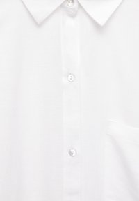 Camicia bianca a bottoni realizzata in tessuto leggero. Presenta un colletto appuntito, sei bottoni e una tasca sul petto. Tessuto liscio.