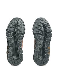 Suole in gomma nera con battistrada profondo, inclusi motivi a zigzag e scanalature. Presenta un design arancione lungo il lato per migliorare la trazione.