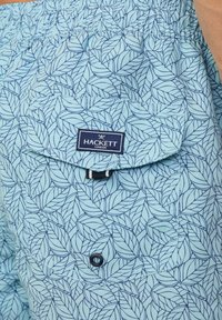 Pantaloni corti azzurri con motivo a foglie, vita elastica, tasca con patta e un piccolo etichetta che recita "Hackett London."