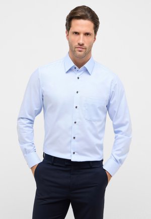 Hellblaues Langarmhemd mit Knopfleiste und Kragen, dunklen Knöpfen und einer Brusttasche. Glatte Textur und maßgeschneiderte Passform.