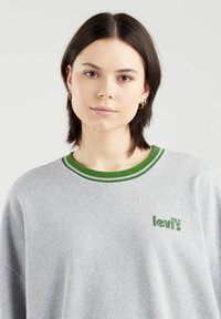 Grå sweatshirt med grønne og hvide striber på kraven, med et grønt "levi's"-logo på brystet. Blødt stof, afslappet pasform.