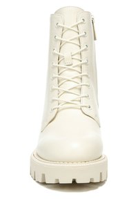 Bottines blanches en cuir avec bout rond, devant à lacets et fermeture éclair sur le côté. Semelle en caoutchouc épaisse avec texture nervurée.
