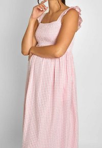 Rosa rutig klänning med en åtsittande smockad överdel, volangärmar och svängd kjol. Lätt tyg med ett rutigt mönster.