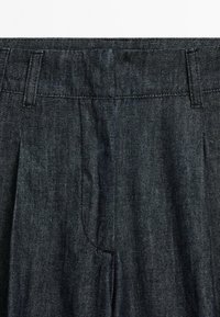 Donkerdenim broek met een geplooide voorkant, recht model en gestikte details. De stof heeft een subtiele textuur en een gemiddelde dikte.