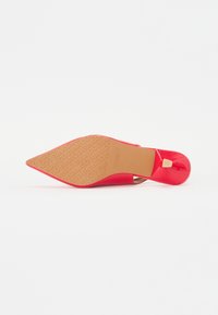 Pantof de piele patent roșie cu toc stiletto, cu vârf ascuțit și talpă din cauciuc bej, având logo-ul brandului embosat. Finisaj strălucitor cu accente minime.