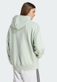 Svetlozelená mikina s kapucňou vyrobená z bavlneného zmesi s rebrovanými manžetami a spodným lemom. Má voľný strih a hladkú textúru.