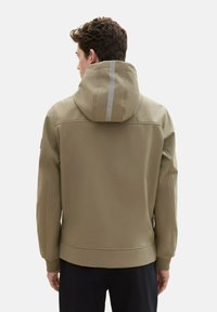 Beige hooded jacket made of smooth material, featuring a silver reflective strip on the hood and ribbed cuffs. Back view shown.