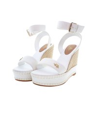 Sandalias de cuña blancas con tiras de tela, un tacón de yute trenzado y una suela suave. Cuenta con una correa en el tobillo con un hebilla metálica.