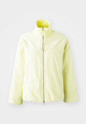 Heled kollane tõmblukkjakker kõrge kraega, ribaga kaelus ja minimalistlik disain. Omab keskset tõmblukku ja ei sisalda nähtavaid mustreid.