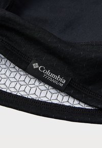 Tejido negro con una capa exterior texturizada, que presenta una etiqueta de Columbia Titanium. El interior tiene un patrón hexagonal en blanco.