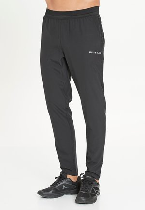 Zwarte sportbroek met een taps toelopend ontwerp, voorzien van een verstelbare taille en logo-opdruk op de linkerdij. Gemaakt van lichtgewicht materiaal.
