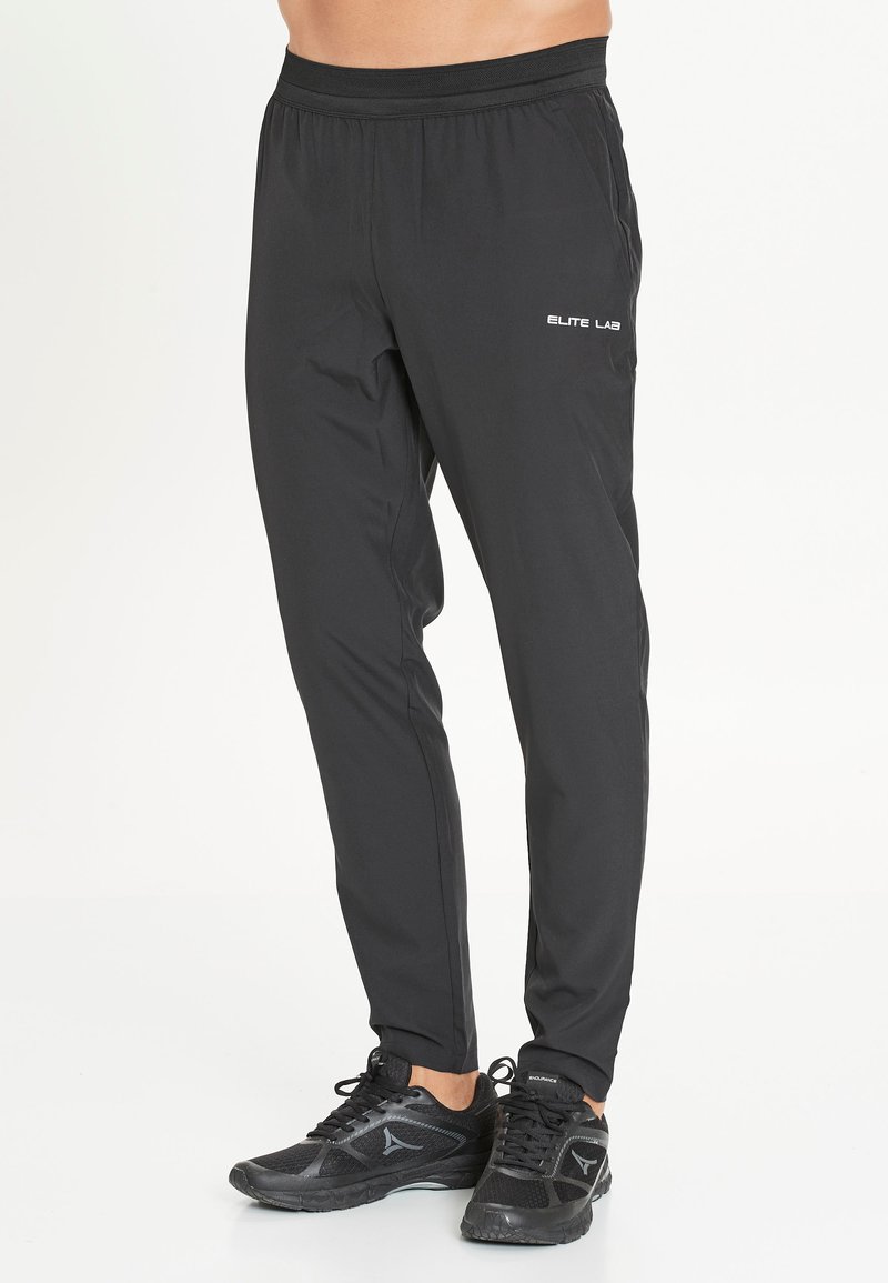 Zwarte sportbroek met een taps toelopend ontwerp, voorzien van een verstelbare taille en logo-opdruk op de linkerdij. Gemaakt van lichtgewicht materiaal.