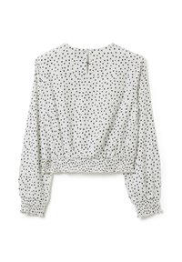 Witte cropped blouse met zwarte hartvormige stippen, lange pofmouwen, elastische onderkant en een knoopsluiting aan de achterkant.