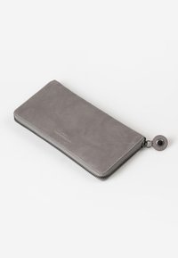 Portafoglio in pelle grigia con chiusura a zip dotata di un accessorio hardware rotondo e testurizzato, finitura liscia e design minimalista.