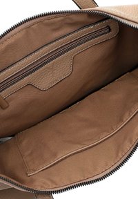 Hnědý kožený interiér tašky s texturou, obsahující kapsu na zip a velký otevřený prostor s hladkou látkovou podšívkou.