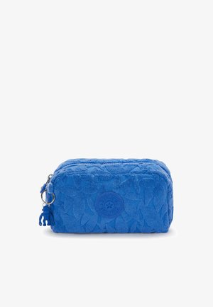 Blauwe rechthoekige cosmeticatas van gestructureerde stof met een bladerenpatroon. Voorzien van een ritsluiting en een rond logo aan de voorkant.