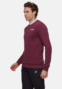 Felpa bordeaux con maniche lunghe, scollatura rotonda, logo discreto sul petto, polsini e orlo a costine, realizzata in un morbido tessuto misto cotone.