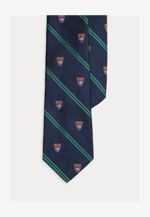 Cravată albastru marin cu dungi diagonale verzi și ștampile repetate cu scuturi roșii și albastre pe toată suprafața materialului.