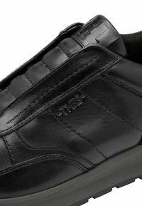 Černá kožená bota s hladkým povrchem, jemným prošíváním a strukturovaným páskem nad nártem. Na boku je výrazně vyražené logo.