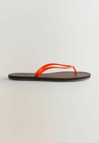 Rudas flip-flop tipo šlepetės su dviem permatomomis raudonomis dirželiais. Tekstūruotas padas su siuvinėta briauna, minimalistinis dizainas ir plokščia profilis.