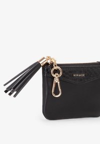 Polsino in pelle nera con finiture in oro, chiusura a zip e dettaglio con nappina. Presenta un pannello superiore lavorato con il nome del brand "MIRIADA".