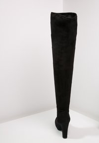 Czarne zamszowe kozaki za kolano o dopasowanym kształcie i smukłym, wysokim obcasie. Gładka textura, minimalne akcenty i prosty design.