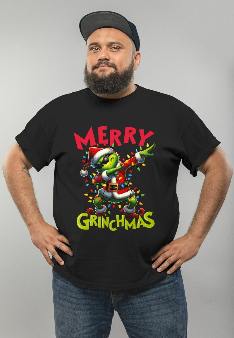 Black t-shirt featuring a colorful Grinch graphic in a Santa outfit, with "MERRY GRINCHMAS" text and Christmas lights design. Cap worn backwards.