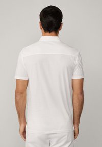 Pánská polo košile s krátkým rukávem v bílé barvě, vyrobená z měkké tkaniny. Obsahuje klasický límec, hladkou strukturu a jemný design zadního yoku.
