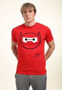 Camiseta de algodón roja con un gráfico en blanco y negro de la cara de un personaje en el frontal. Mangas cortas, ajuste estándar.