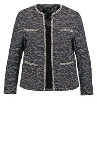 Svart och vit tweedjacka med rund halsringning, två framfickor och rak passform; har kontrasterande texturerad kant längs kanterna.