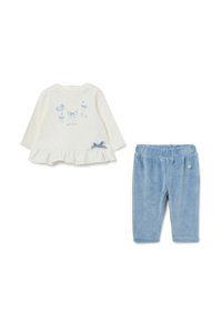 Ensemble en deux pièces composé d'un haut à manches longues blanc avec un graphique d'ours et d'un pantalon en velours bleu. Le haut a des volants et des accents de nœud bleu.