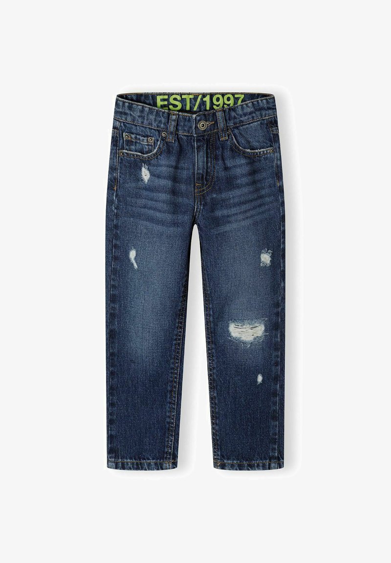 Tumši zilo džinsu bikses ar brīvu piegriezumu, nolietotu izskatu, piecu kabatu dizainu un zaļu EST/1997 uzlīmi uz jostas.