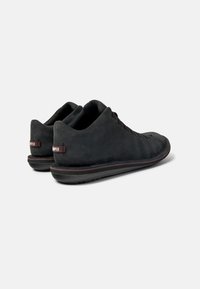 Scarpe in suede nero con una texture liscia, forma arrotondata, design minimalista e etichette rosse di accento sul retro. Suole in gomma per una migliore aderenza.
