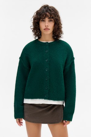Cardigan vert, tricot épais avec un col rond, des manches longues et sept boutons assortis sur le devant. Tissu texturé et douillet.