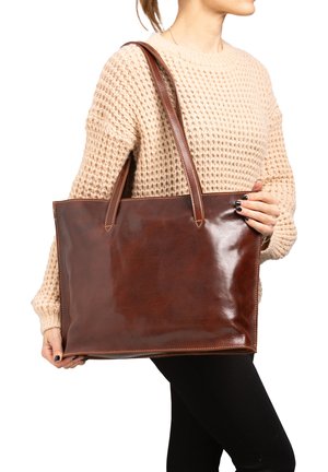 Bruine leren tote bag met een gladde afwerking. Voorzien van lange handvatten en een rechthoekige vorm, met gestikte details langs de randen.