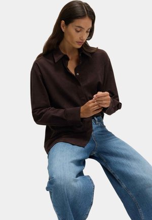 Brun skjorte med knaplukning og krave, afslappet pasform og lange ærmer, sat sammen med lyseblå vidde jeans. Minimalistisk design og glat tekstur.